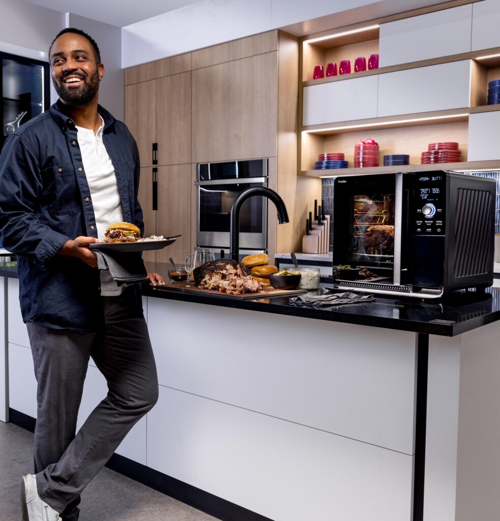 Man enjoying a meal in a modern kitchen with the GE Profile Indoor Smoker.